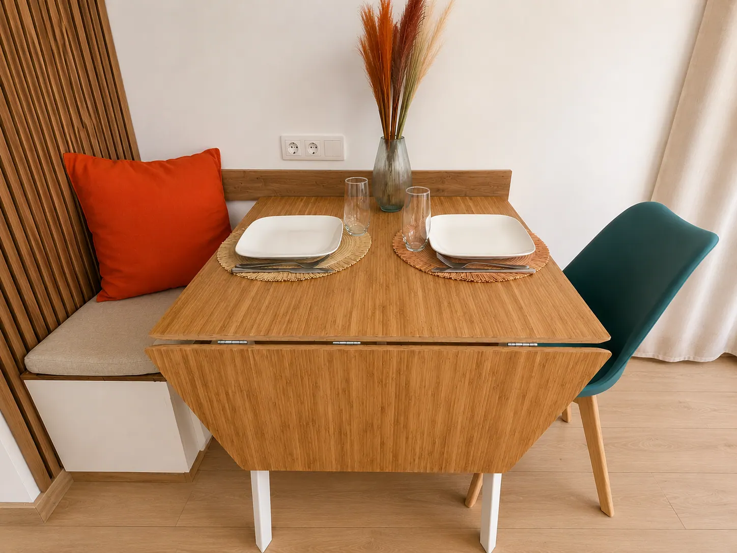 Espace repas avec banquette bois, table extensible et coussin terracotta