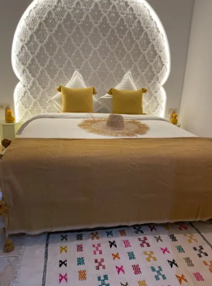 Chambre du Riad SAFYA avec tête de lit arabesque rétroéclairée et tapis berbère